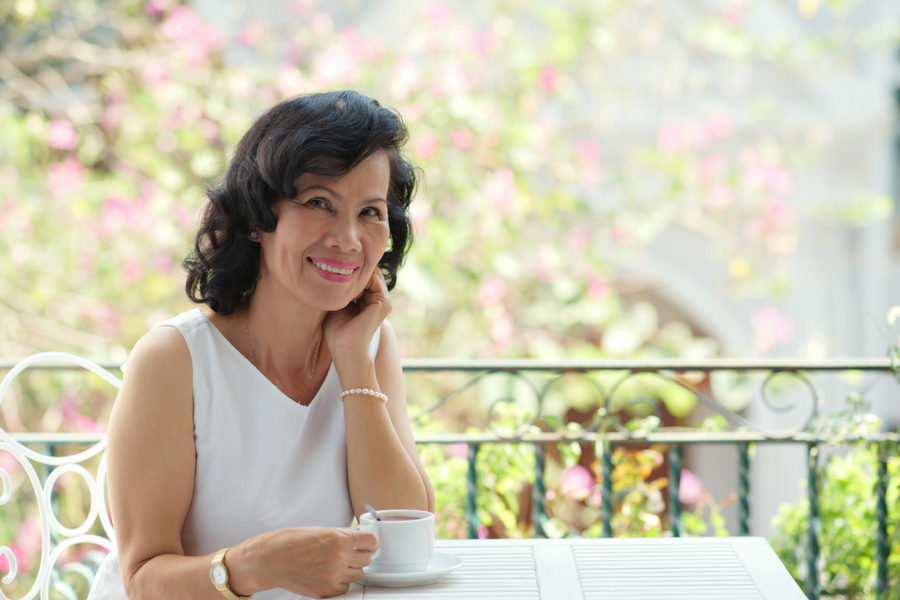 A woman is sitting at a table holding a cup of coffee.